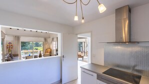 Una cocina moderna con lavavajillas incorporado, extractor de acero inoxidable y un amplio ventanal con vistas a un balcón.