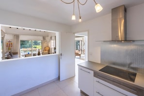 A modern kitchen with a built-in dishwasher, a stainless steel range hood, and a large window overlooking a balcony.