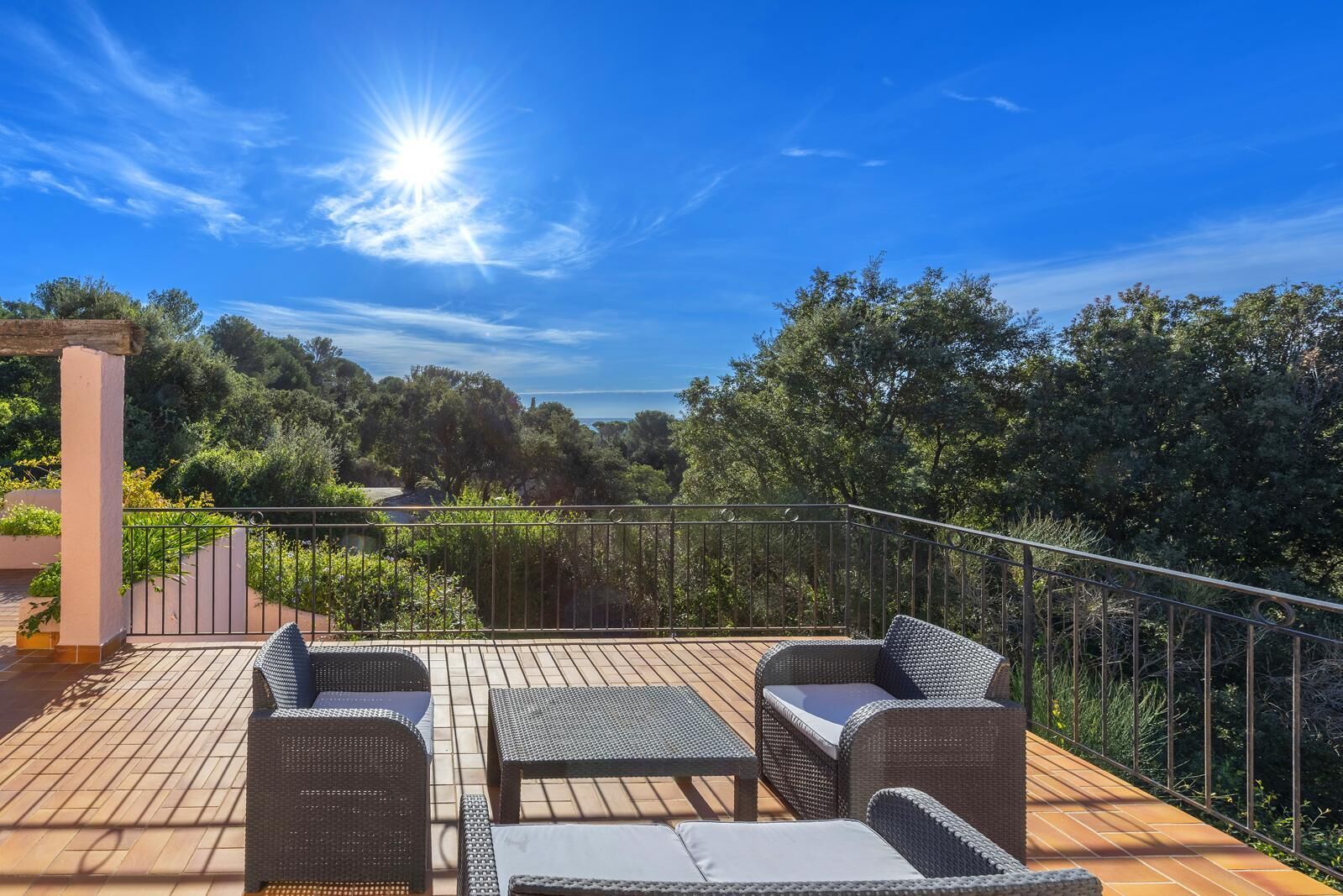 A deck with wicker furniture and a view of the surrounding greenery.