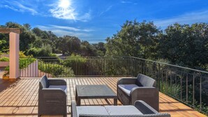 Una terraza con mobiliario de mimbre y vistas a la vegetación circundante.