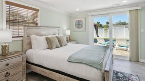 Un dormitorio con una cama grande, una mesita de noche, una lámpara y vistas a una piscina y zona exterior.