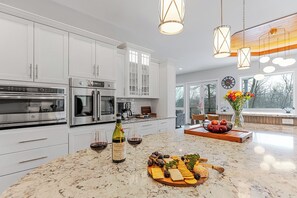 A modern kitchen with white cabinets, stainless steel appliances, and a marble countertop. - Sundrift Escape ~ 6BR Luxury Retreat ~ Hot Tub/Sauna/Game Room/Arcade/Golf Cart (Lake Harmony)