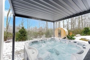 Ein Whirlpool in einem überdachten Außenbereich mit Blick auf Bäume und einer Holzkonstruktion im Hintergrund.