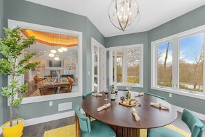 A dining room with a round table, green upholstered chairs, and a chandelier. - Sundrift Escape ~ 6BR Luxury Retreat ~ Hot Tub/Sauna/Game Room/Arcade/Golf Cart (Lake Harmony)
