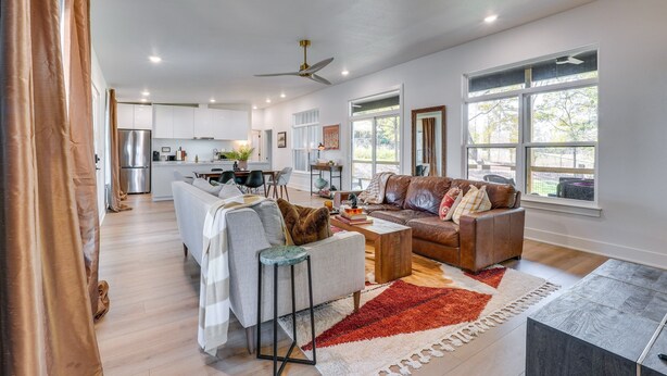 A spacious living room with a sofa, coffee table, and a fireplace. There is a kitchen in the background with modern appliances.