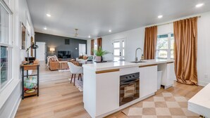 A modern kitchen with a central island, white cabinetry, and a built-in oven.
