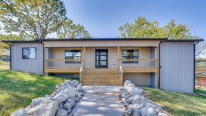 A modern two-story house with a wooden deck, a front porch, and a concrete pathway leading to the entrance.