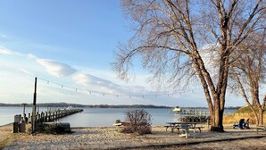 En park vid sjön med en träbrygga, picknickbord och en båtbrygga.