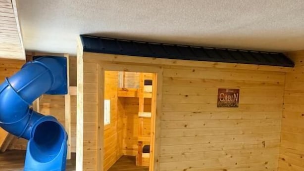 A cabin interior with a wooden floor, a blue slide, and a sign reading "CABIN". - Lake Lawn Inn (Pana)
