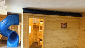 A cabin interior with a wooden interior, a blue slide, and a sign reading "Welcome to Cabin". - Lake Lawn Inn (Pana)