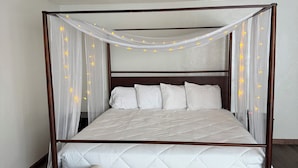 A four-poster bed with a canopy, white bedding, and a tufted bench at the foot. - Lake Lawn Inn (Pana)