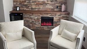 A living room with a stone wall, a fireplace, and two armchairs. - Lake Lawn Inn (Pana)