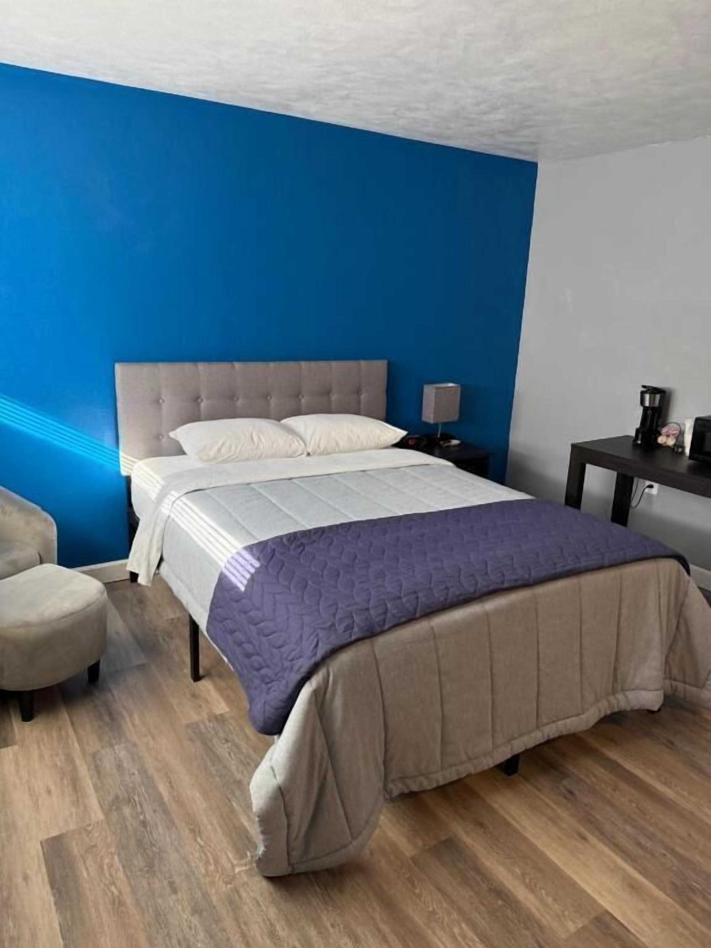 Une chambre à coucher comprenant un lit, une table de chevet, une chaise et un bureau.