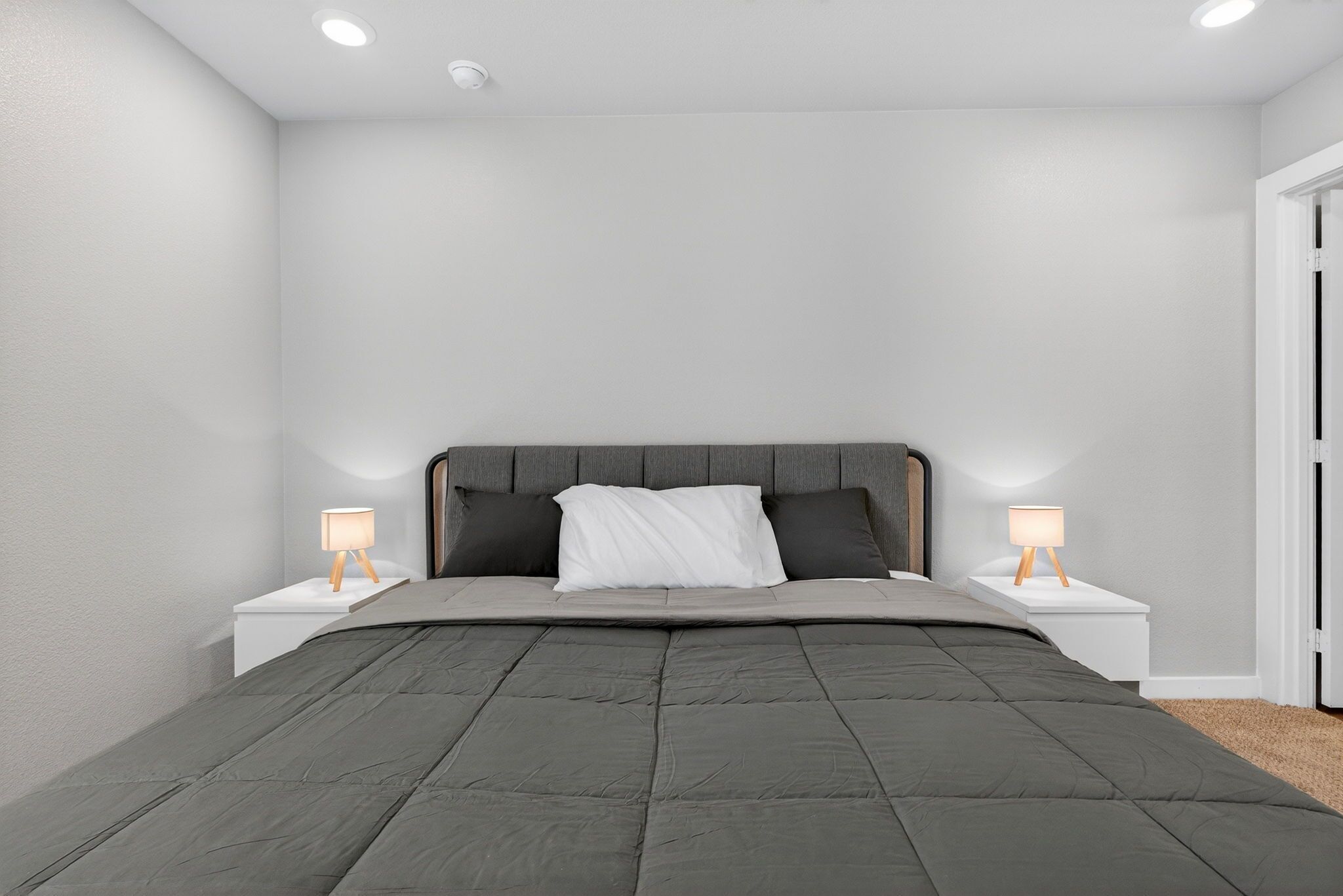 A bedroom with a bed, two bedside tables, and two wall-mounted lamps.
