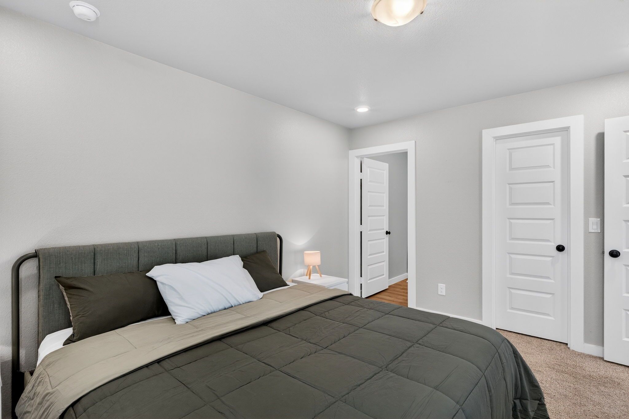 A bedroom with a bed, a nightstand, and a door.