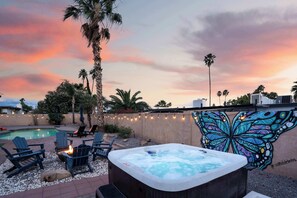 Ein Garten mit Whirlpool, Liegestühlen, Schwimmbecken und einem Schmetterlingsgemälde.