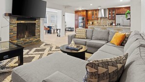 Una sala de estar moderna con chimenea, un sofá gris y un televisor de pantalla plana.