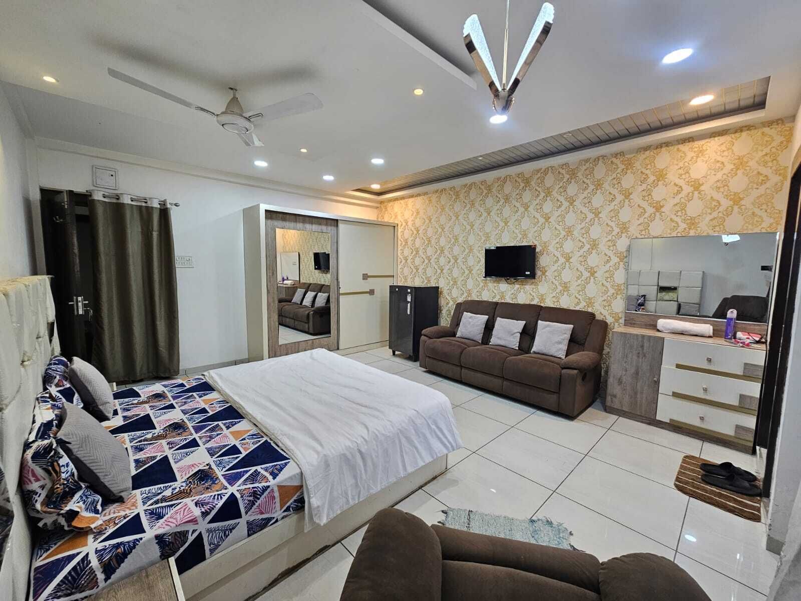A modern bedroom with a bed, a sofa, a TV, and a wardrobe.