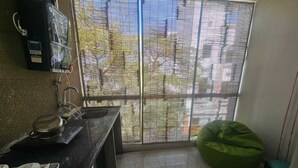 A small kitchen with a sink, a stove, and a green bean bag chair. - Cozy 1-bedroom fabulous studio in Indore with all amenities. (Indore)