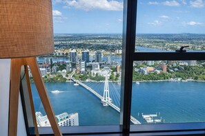 A view from a high-rise window overlooking a cityscape with a prominent bridge and a body of water. - Comfortable 2BR City Apartment | Walk Everywhere (Brisbane)