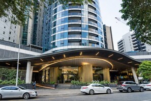A modern hotel entrance with a curved canopy, large columns, and a view of surrounding high-rise buildings. - Comfortable 2BR City Apartment | Walk Everywhere (Brisbane)