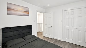 Un dormitorio con cama, puertas blancas y un cuadro en la pared.