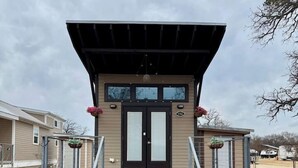 A building with a covered entrance, two doors, and a small porch area with steps. - Little Luxe Hideaway with Pool & Hot Tub (Austin)