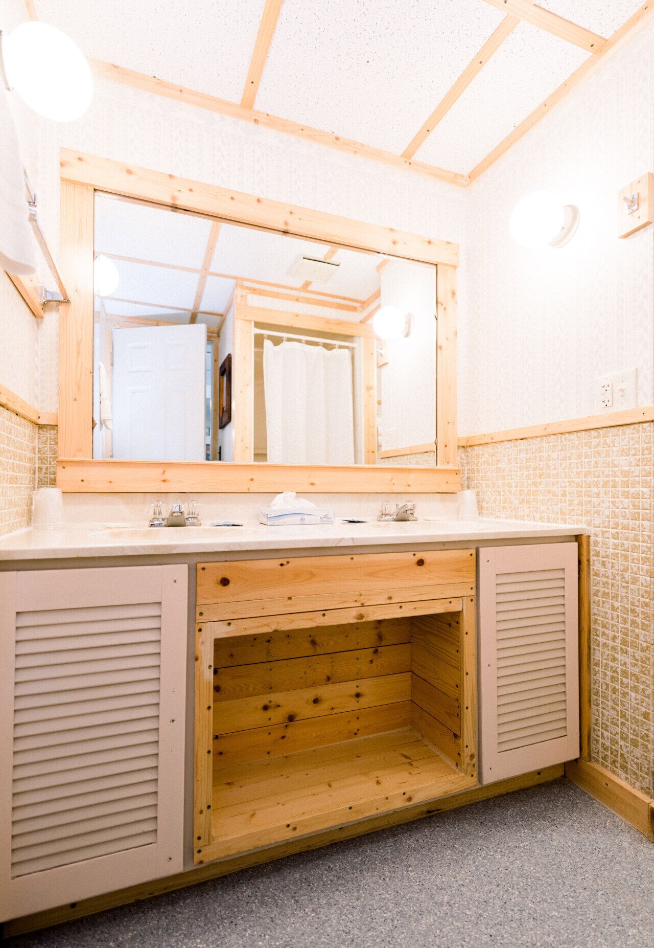 Un baño con tocador de madera, un espejo grande y salpicadero de azulejos.