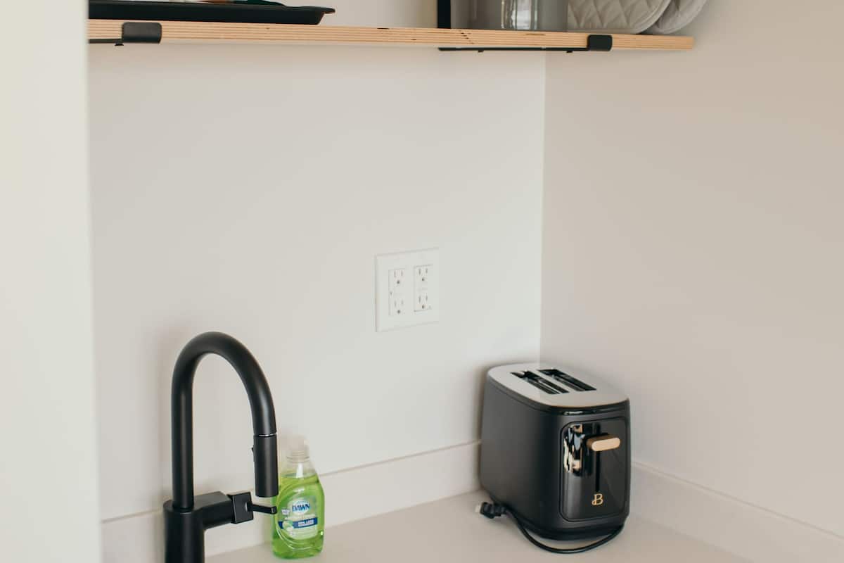 A kitchen with a white countertop, a sink, a toaster, and a dish rack.
