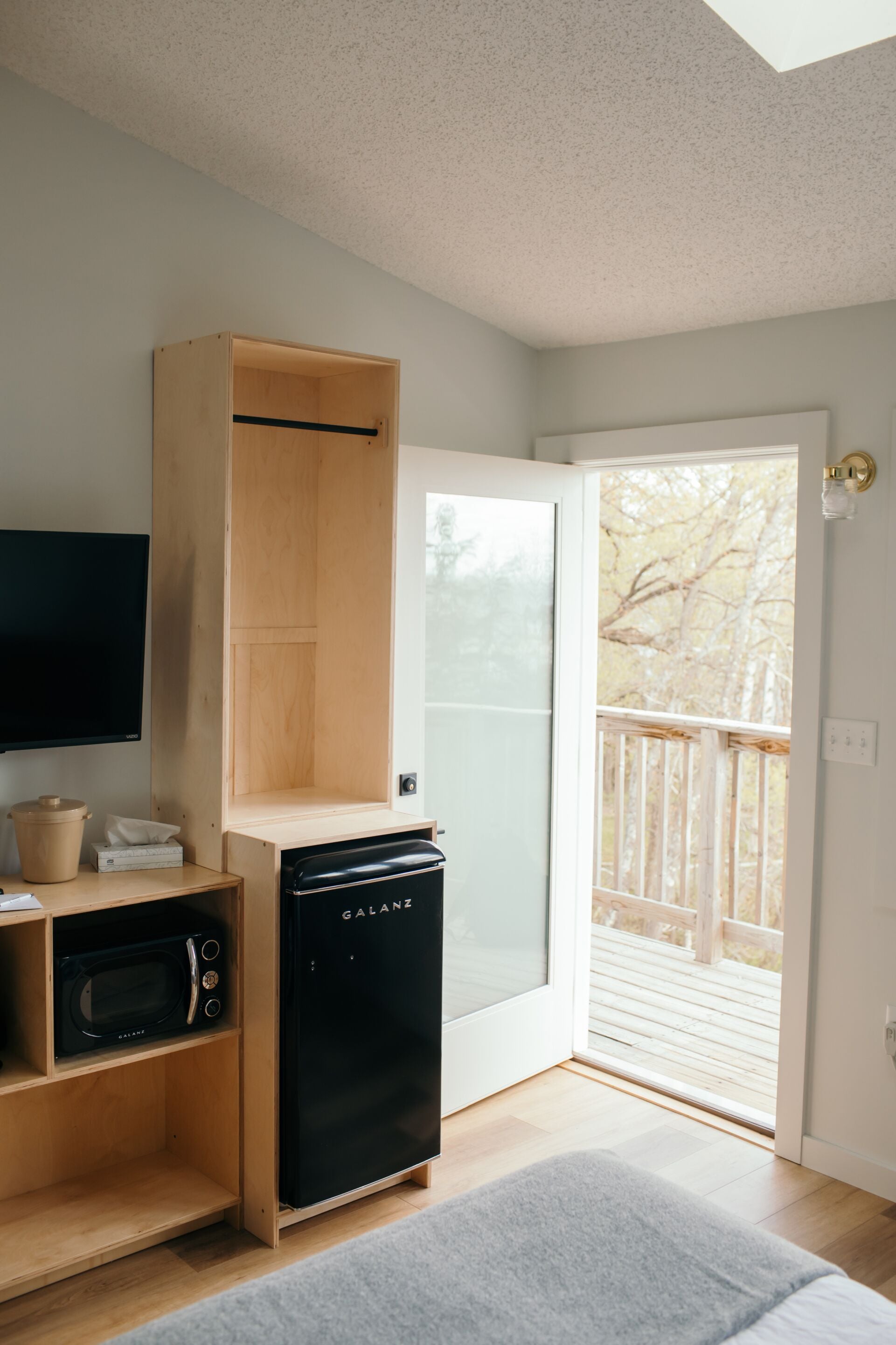 A compact kitchen with a built-in microwave, a black dishwasher, and a wooden cabinet.