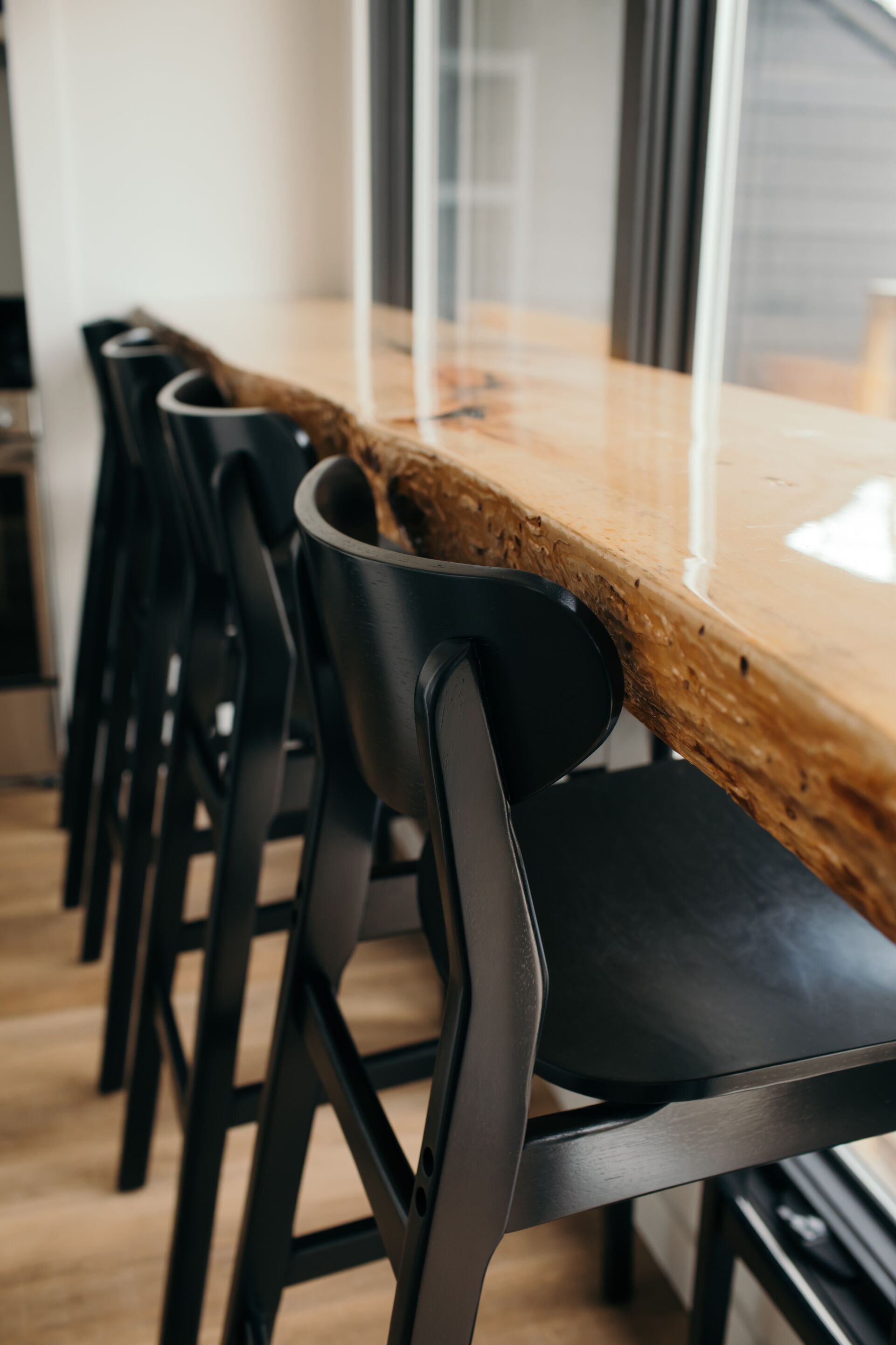 A conference table with chairs, a wooden top, and a glass partition.