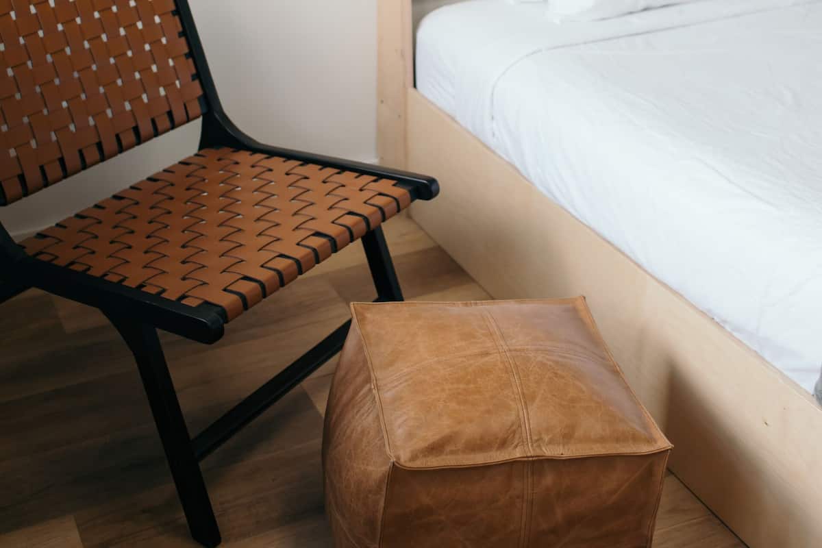 A bedroom with a wooden headboard, a brown leather chair, and a matching ottoman.