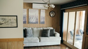 Ein Wohnzimmer mit einer Couch, Holzboden, einem Chandelier und einem großen Fenster mit Blick.