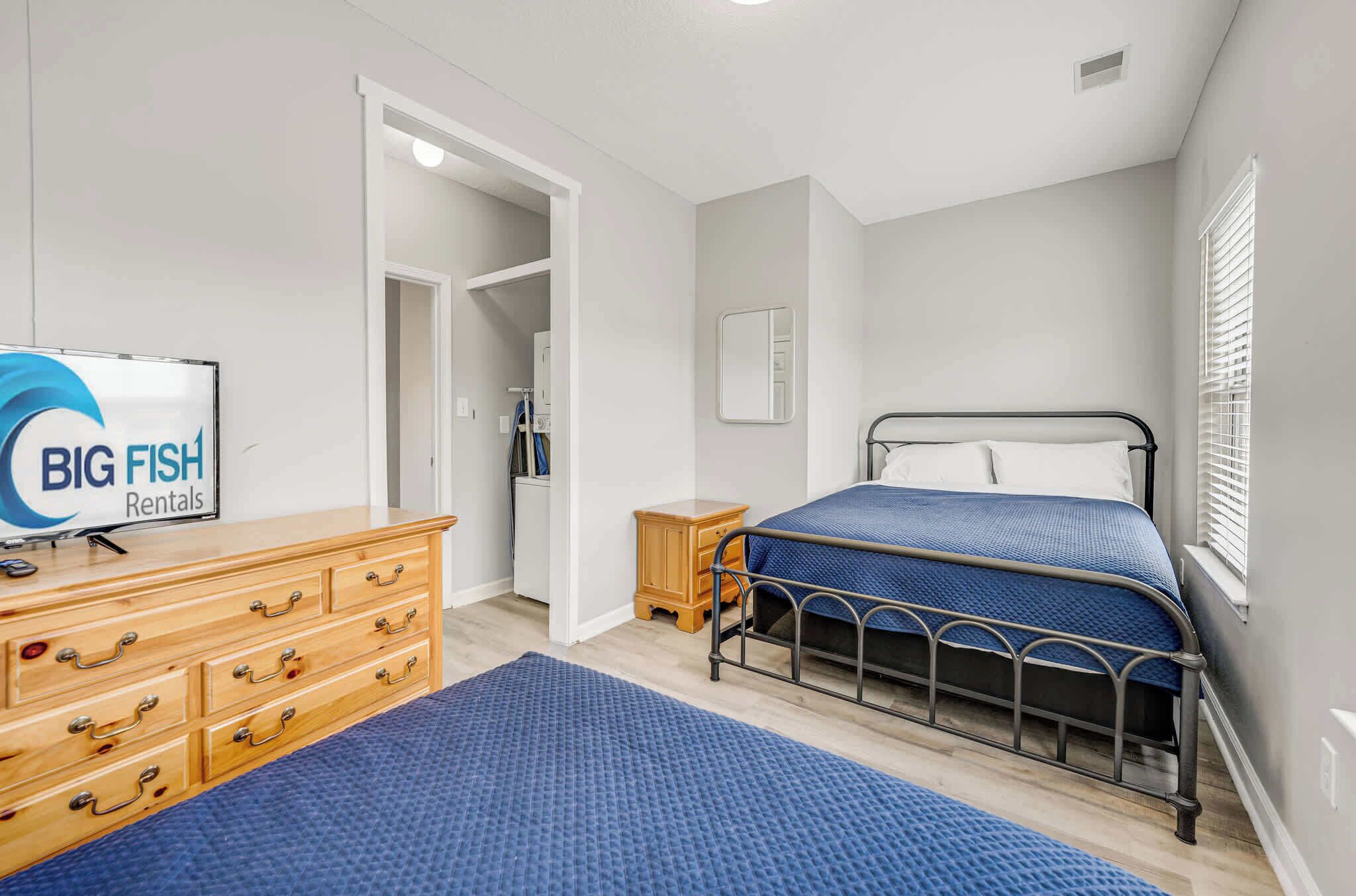 Un dormitorio con cama, cómoda, televisor y un cartel de Big Fish Rentals.