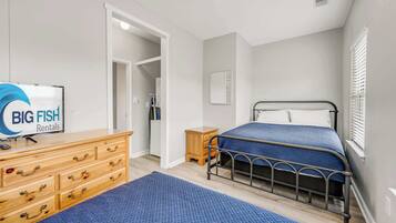 Un dormitorio con cama, cómoda, televisor y un cartel de Big Fish Rentals.