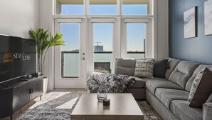 Ein modernes Wohnzimmer mit großem Fenster, Flachbildfernseher, Sofa und Couchtisch.