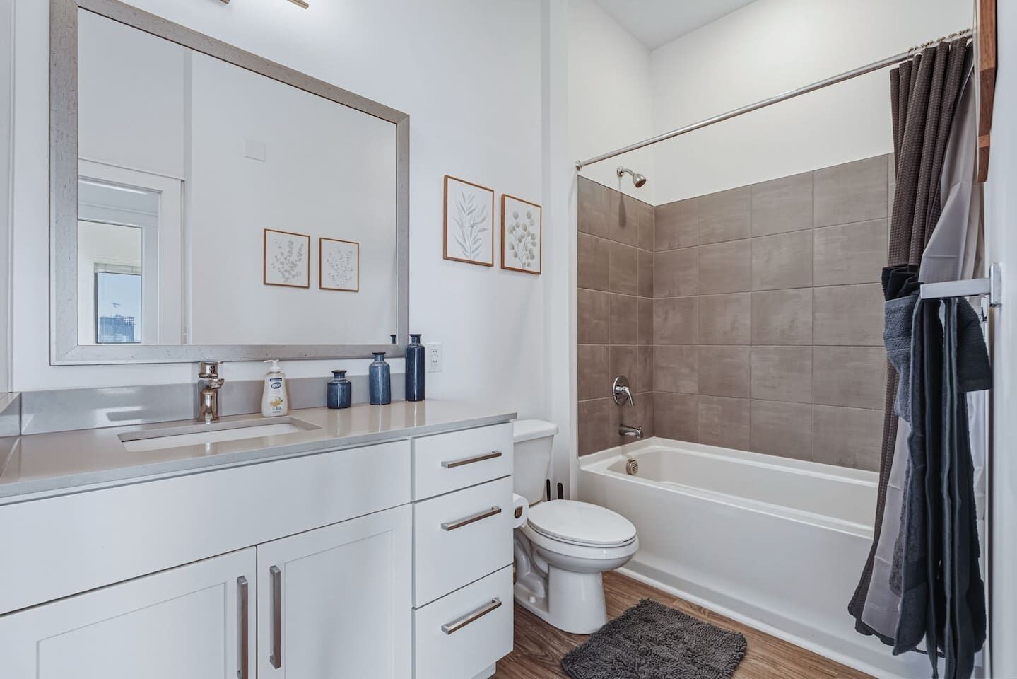 Ein modernes Badezimmer mit Badewanne, Toilette und Waschtisch inklusive Spiegel und gerahmten Bildern.