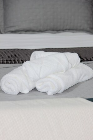 A neatly folded white towel on a bed with a grey textured bedspread. - Furnished studio apartment near the US Consulate, Interlagos, Morumbi Shopping Mall, and Brooklin metro station. (São Paulo)