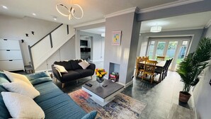 A modern living room with a sofa, coffee table, and a dining area with chairs and a table.