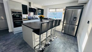 A modern kitchen with a central island, stainless steel appliances, and a bar stool seating arrangement.