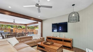 Ein modernes Wohnzimmer mit einem großen Ecksofa, einem Holztisch und einem an der Wand befestigten Flachbildfernseher.
