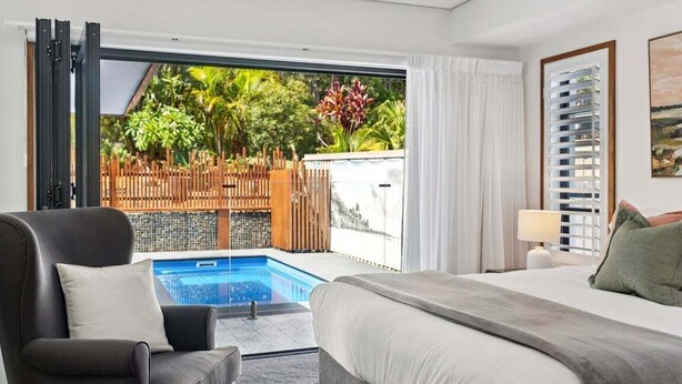 Ein Hotelzimmer mit Bett, Stuhl, Schreibtisch und Blick auf einen Swimmingpool und Außenbereich.