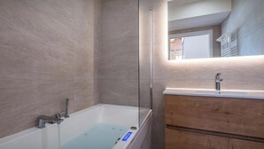 Une salle de bain moderne avec une douche en verre, une baignoire blanche et un meuble-lavabo en bois doté d’un miroir.