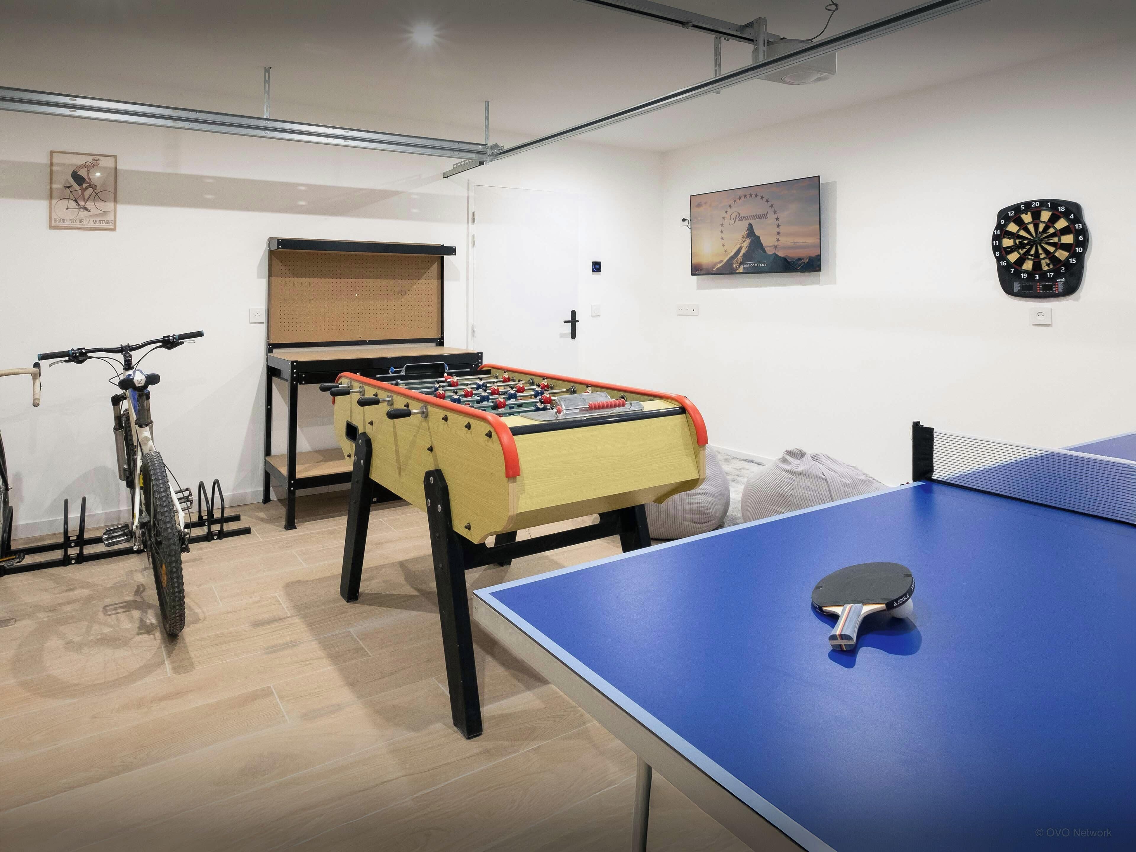Una habitación con mesa de fútbol de mesa, mesa de ping pong y un soporte para bicicletas.