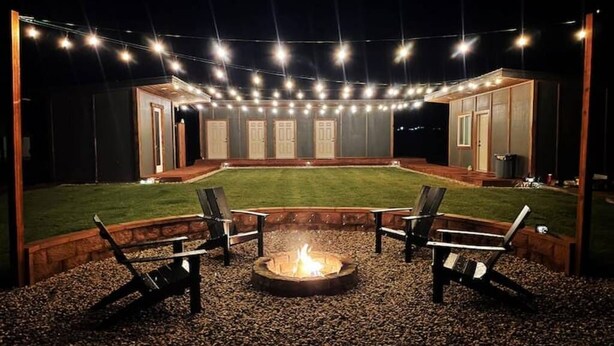 Un patio al aire libre con una chimenea, asientos e iluminación con guirnaldas.