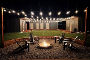 Un patio al aire libre con una chimenea, asientos e iluminación con guirnaldas.