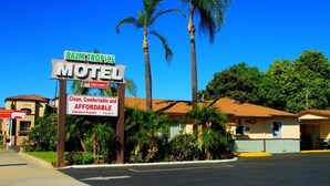 Een motel genaamd Palm Tropics, met een bord waarop staat dat er kamers beschikbaar zijn.