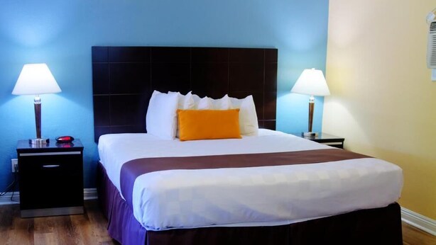 Een hotelkamer met een groot bed, twee nachtkastjes met lampen en een donker hoofdeinde.