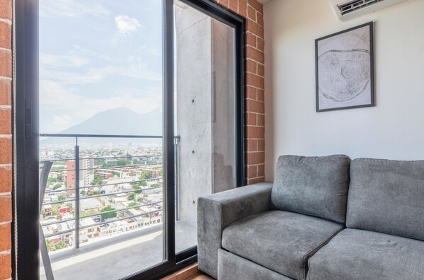 A balcony with a city view, a grey sofa, and a framed artwork on the wall. - Barrio Vergel (Monterrey)