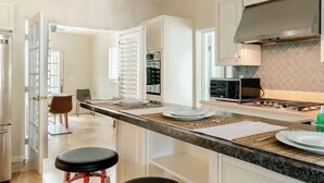 Une cuisine moderne avec des armoires blanches, un comptoir en granit et une hotte de cuisinière en acier inoxydable.